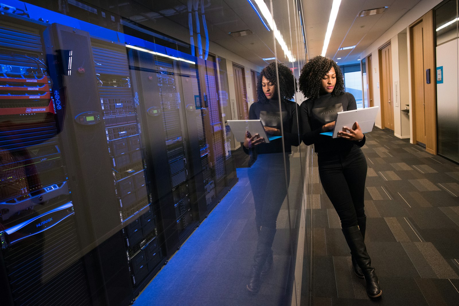 Professionnelle de la cybersécurité consultant une tablette dans une salle serveurs
